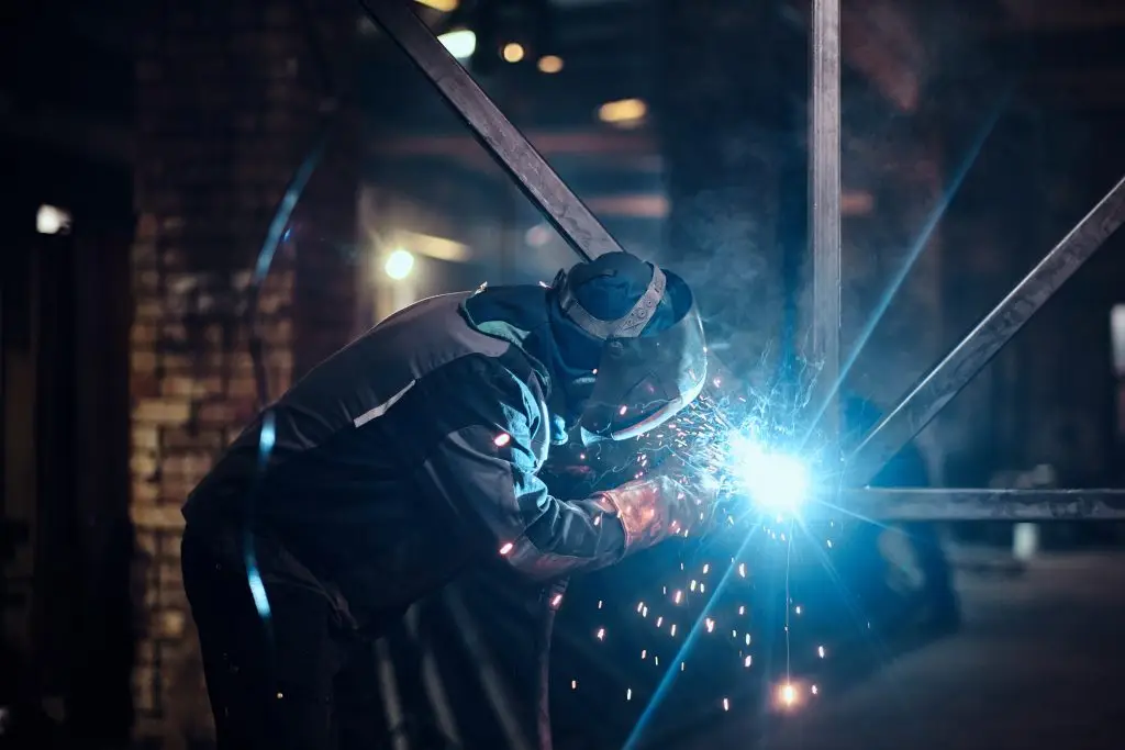 Welding work with metal construction at busy metal factory by Poullaides Construction