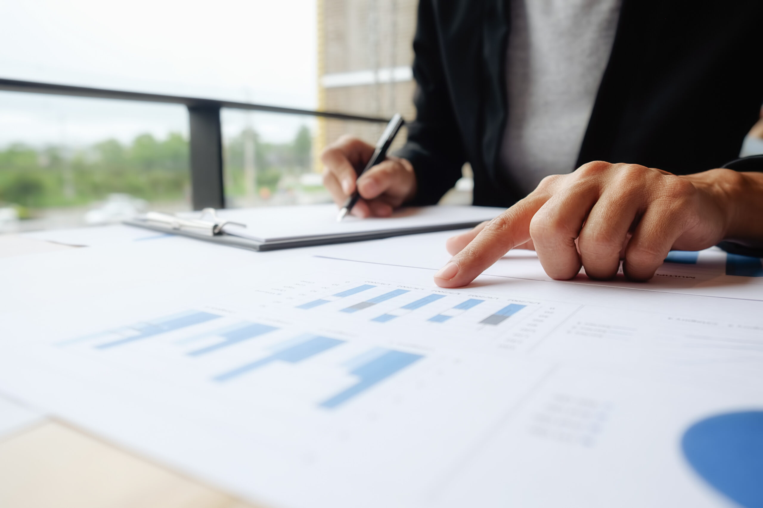 Asian woman manager putting her ideas and writing business plan at workplace, making notes in documents on the table in office, vintage color, selective focus. Business concept.