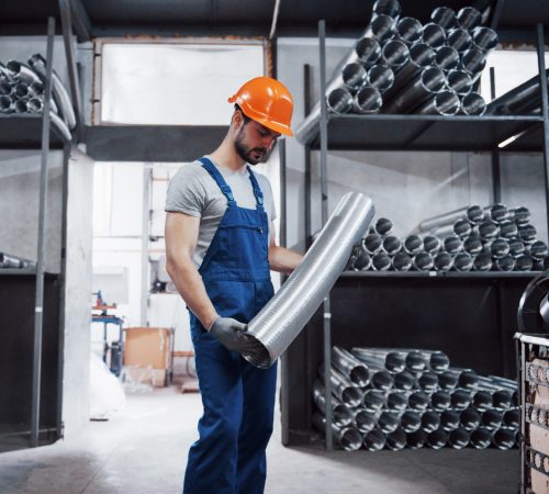 Portrait of a young worker in a hard hat at a large metalworking plant. Shiftman on the warehouse of finished products.